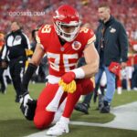 Travis Kelce catching a football during an NFL game, on bended knee